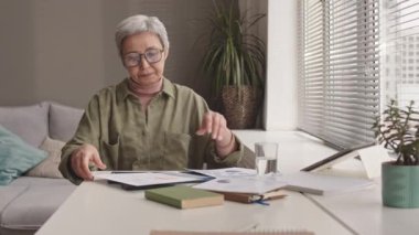 Gözlüklü, meşgul Asyalı kadından uzaklaşmak pencere kenarında oturup belgelerle çalışmak.