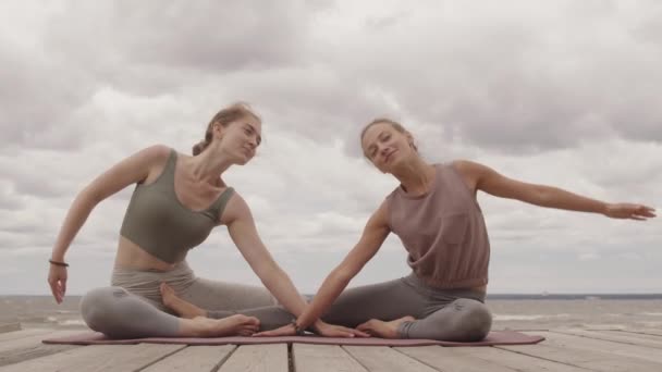 Twee Jonge Gezonde Vrouwen Sportkleding Beoefenen Paaryoga Samen Zittend Houten — Stockvideo