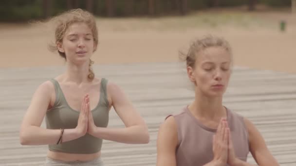 Slowmo Medium Close Two Young Women Sitting Lotus Pose Praying — Stock Video