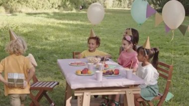 Sarışın erkek arkadaşın, Sunny Park 'ta çocuklarla ve kadınlarla aynı masada oturan melez doğum günü çocuğuna hediye vermesi.