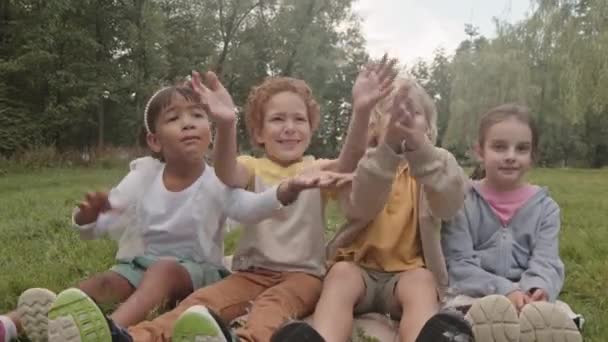 Bajo Ángulo Cuatro Escolares Grado Multiétnico Sentados Juntos Césped Parque — Vídeos de Stock