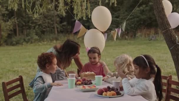 中等个子的白人年轻女子为5岁的女儿做生日蛋糕 孩子们在公园的桌子边拍手 — 图库视频影像