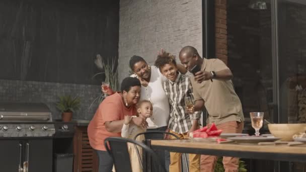 跟踪坐在餐桌旁的一家五口人的快乐的非洲裔美国人 他们使用智能手机 面带微笑地自言自语 — 图库视频影像