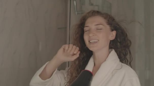 在大理石浴室烘干长卷发的同时 年轻美丽女子歌唱的中等特写镜头 — 图库视频影像