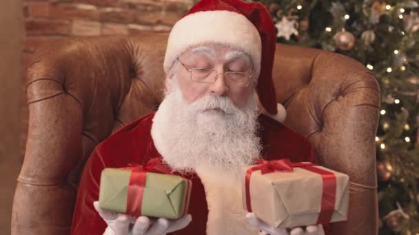 Chest Santa Clause Sedí Doma Křesle Drží Dvě Malé Dárkové — Stock video