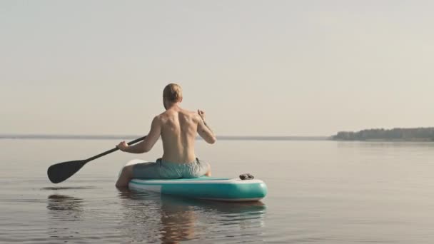 Vista Trasera Lenta Del Joven Atlético Sentado Tablero Sup Paddle — Vídeo de stock