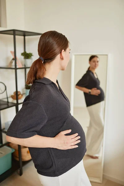 Těhotná žena se dívá do zrcadla — Stock fotografie