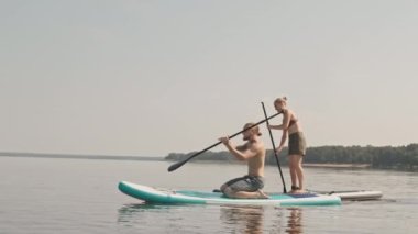 Yaz günü gölde kürek çeken genç ve sportif çiftin yavaş çekim görüntüleri.
