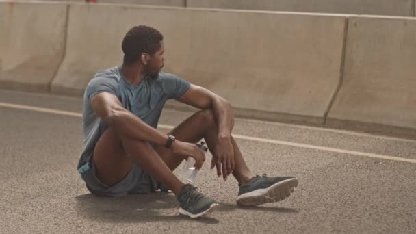 Lento Disparo Hombre Afroamericano Cansado Sentado Suelo Puente Ciudad Agua — Vídeos de Stock