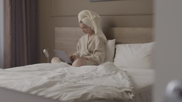 현대식 아파트 침대에 노트북 컴퓨터로 일하고 여성의 방탄복을 수건을 채찍은 — 비디오