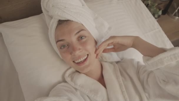 Kafasında Bornoz Havluyla Beyaz Yatakta Kameraya Gülümseyen Mutlu Beyaz Bir — Stok video