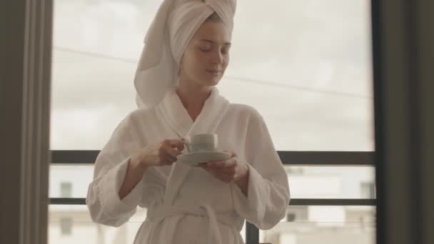 パノラマの窓に風呂やシャワースタンドを持っていた後 幸せな若い女性が朝のコーヒーを楽しんでのローアングル中出しを傾けます — ストック動画