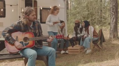 Çok ırklı gençlerin, ormanda tekerlikli evlerin etrafında toplanıp gitar çalarken, sohbet ederken ve bira içerken, yazları birlikte geçirdikleri el kamerası görüntüleri.