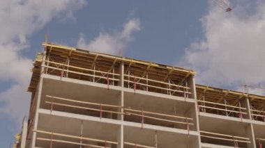 Güneşli bir günde, çok katlı bina ve vinçlerin inşaat alanının solundaki düşük açılı izleme