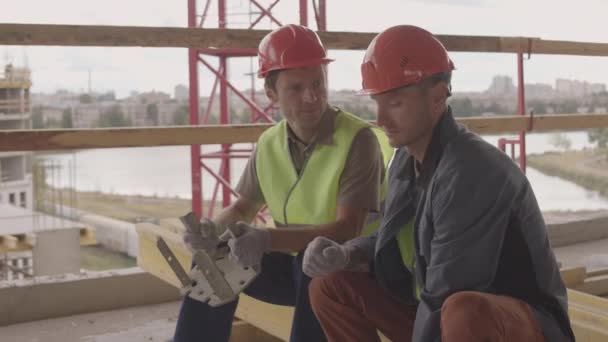 Longo Tiro Médio Dois Construtores Caucasianos Usando Capacetes Laranja Sentado — Vídeo de Stock