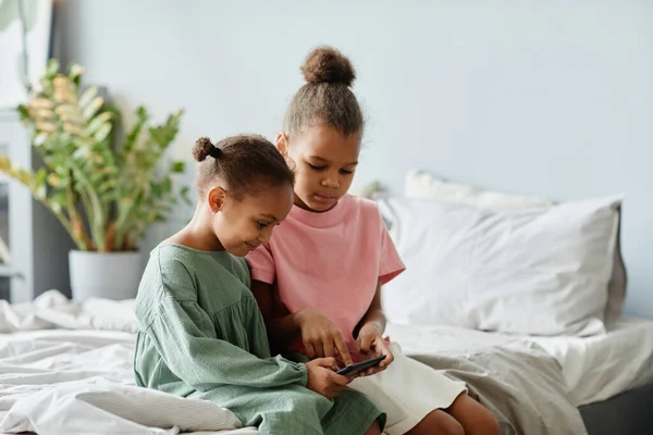 Дві маленькі дівчата використовують смартфон вдома — стокове фото