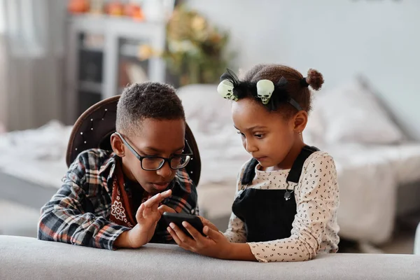 Двоє дітей користуються смартфоном вдома. — стокове фото
