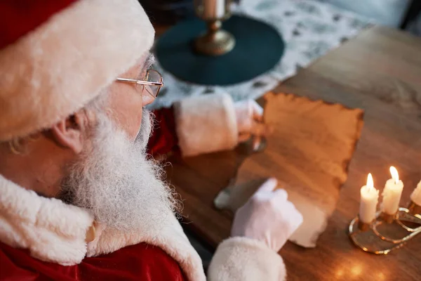 Santa Čtení písmeno pod svíčkou — Stock fotografie