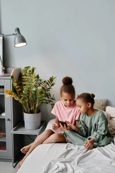 Дві афроамериканські дівчини вдома користуються смартфоном — стокове фото