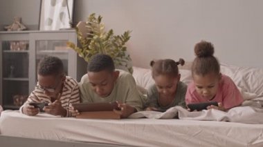 Dört bağımlı Afro-Amerikan okul öğrencisinin yavaş çekimleri. Rahat yataklarında yatıyorlar. Üzerlerinde sanal oyunlar oynuyorlar.