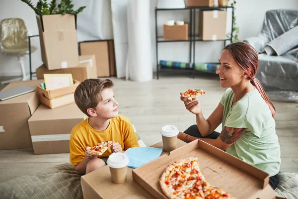 Madre e hijo comiendo pizza en un nuevo hogar —  Fotos de Stock