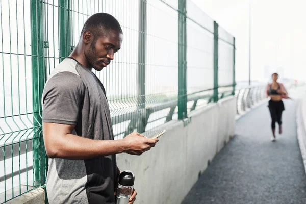 Atleta africano usando el teléfono al aire libre — Foto de Stock