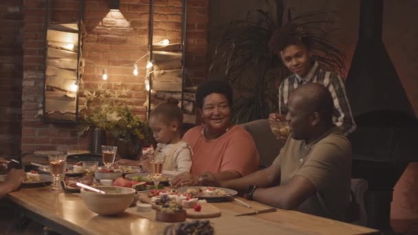 中长的快乐的非洲少年男孩在家里的饭厅里为家人端沙拉 — 图库视频影像