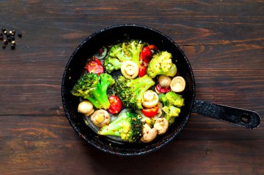 Ahşap arka planda otantik tavada sebze karışımı. Dünya Vegan Günü veya Sağlıklı Yeme Konsepti.