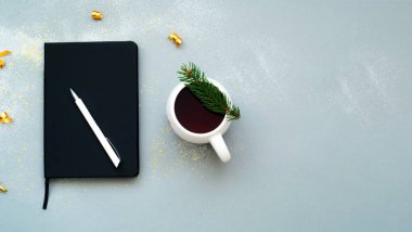 Kıvılcımlı, gri bir arka plan. Beyaz seramik bardakta çay ve gol-ayarlayıcı defter. Planlama konsepti. Yaratıcı kopyalama alanı.