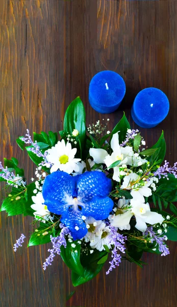 Valentines Day concept. Beautiful bouquet of spring flowers and blue candles on wooden background. Stock Photo