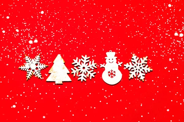 Slavnostní červené pozadí s jiskry. Vánoční dřevěné figurky na zasněžené textuře. Domácí vánoce.Kreativní kopírovací prostor. — Stock fotografie