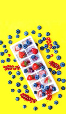 Sarı arka planda ev yemeği için meyve ve böğürtlenlerden dondurulmuş ürünler. Yakın plan, yaratıcı kopya alanı, moda rengi 2021