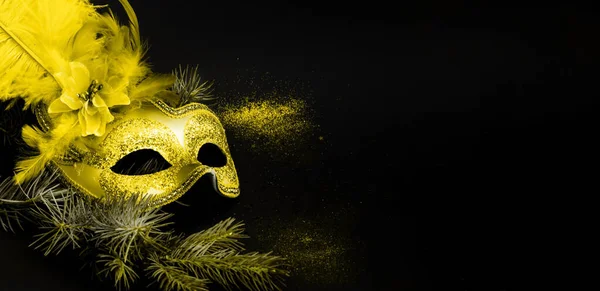IIlluminating Yellow masquerade mask on dark background with confetti. Trendy color 2021. Creative copy space. Close-up