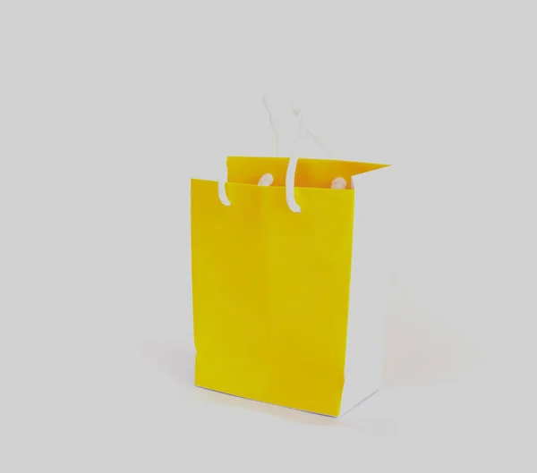 Saco de compras de papel amarelo brilhante em fundo isolado branco. Decoração festiva . — Fotografia de Stock