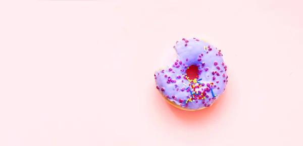 Rosquillas de colores con salpicaduras de colores sobre fondo rosa. Concepto del Día Nacional de Donuts o Donuts. Copiar espacio — Foto de Stock