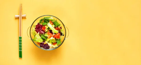 Salade Salmon Poke dans un bol en verre et baguettes sur fond jaune. Couleurs tendance 2021. Espace de copie créative. — Photo