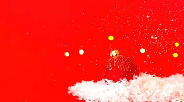 Bugiganga de Natal vermelho na textura da neve. Cartão de Natal com lugar para o seu texto. — Fotografia de Stock