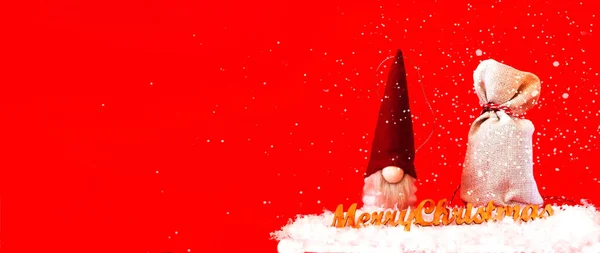 Brinquedo de Natal Papai Noel e um saco com presentes em um fundo vermelho.Cartão de Natal. Espaço de cópia criativa. — Fotografia de Stock