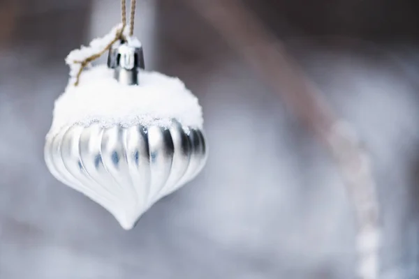 Christmas toy hanging on a branch in a snowy forest. Macro photo. Blurry background.Selective focus