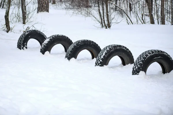 Automobile tire. Five car tires are standing in the snow in the winter forest. The concept of security of the car: winter tires, fifth wheel ice — Stock Image Automobile Tire Five Car Tires Standing Snow Winter Forest Concept Stock Photo