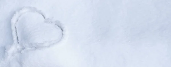 One heart in the snow. A heart is drawn on the snow close-up, there is an empty space for text on the right. Banner. Winter background.
