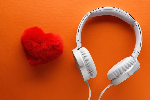 Red heart and white headphones on a orange background. Love music lifestyle concept. Valentine\'s Day