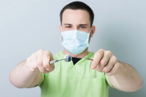 Dentista masculino posando segurando moedor e espelho — Fotografia de Stock