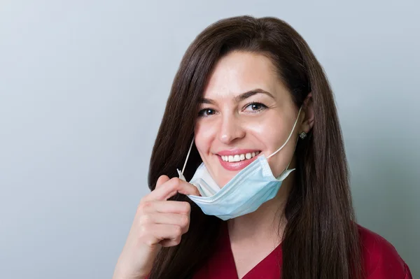 美しい女性歯科医がマスクを取り外し、笑顔を見せた — ストック写真