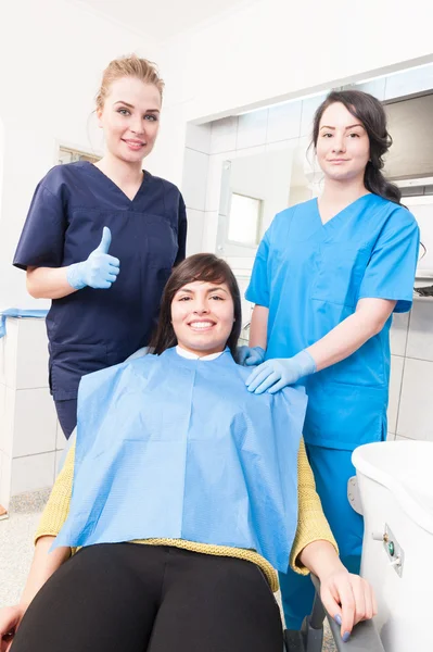 Allegra donna dentista thumbup mentre paziente e assistente sono s — Foto Stock