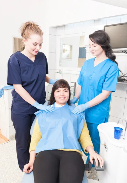 Beautiful doctor and assistant with smiling patient in dental of — Stock Photo, Image