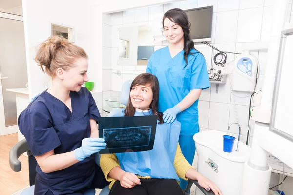 Hastaya x ışını görüntüsünü gösteren kadın diş hekimi ve asistanı 