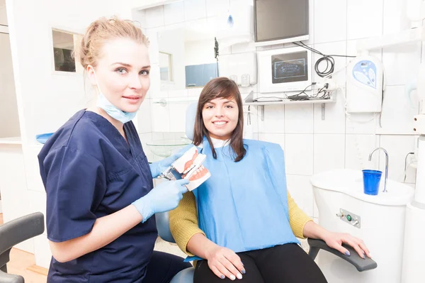 Beautiful female dentist with plastic jaw imitation and toothbru — Stock Photo, Image