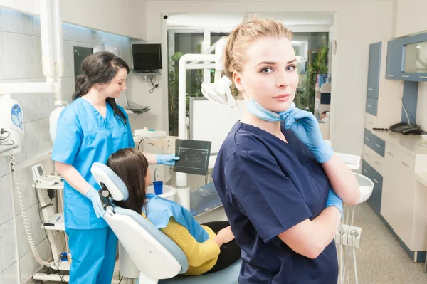 Selbstbewusste Zahnärztin posiert mit weiblicher Assistentin, die x-r hält — Stockfoto