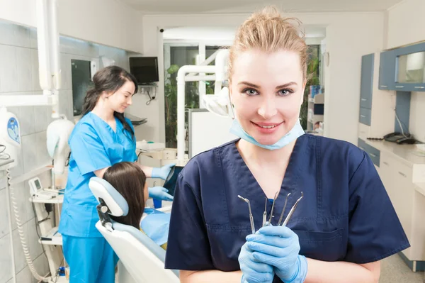 Dentista feminina atraente com ferramentas dentárias na mão — Fotografia de Stock